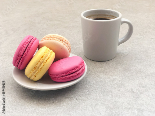 olorful delicious macaroons and cup of coffee on gray table