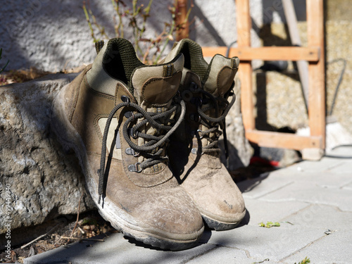 Men's work shoes. It is dirty and leaning on an outdoor flowerpot.