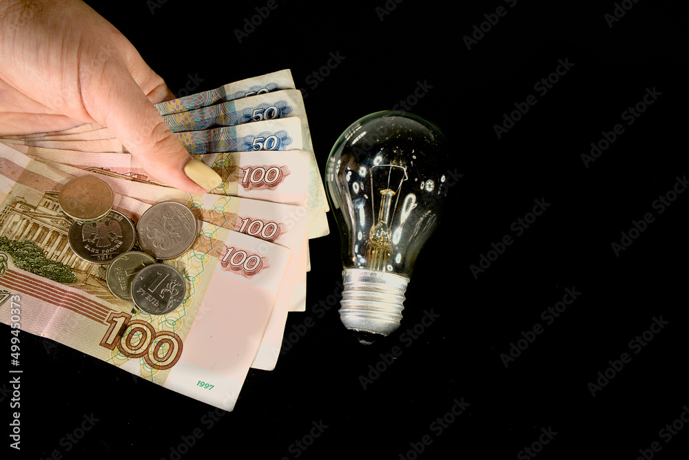 The concept of the cost of electricity. Electric lamp and money of russian rubles The concept of the cost of electricity. Electric lamp and money of russian rubles