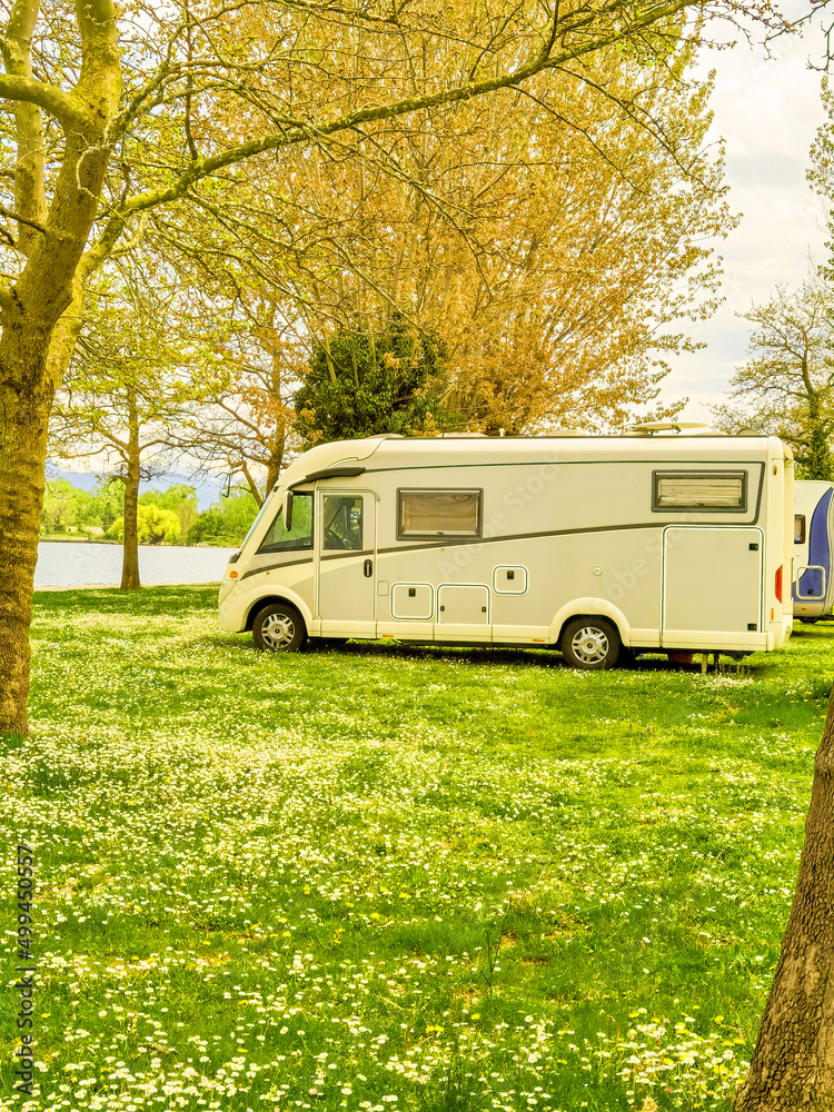 caravan car in the trees among flowers by the lake in spring caravan car in the trees among flowers by the lake in spring