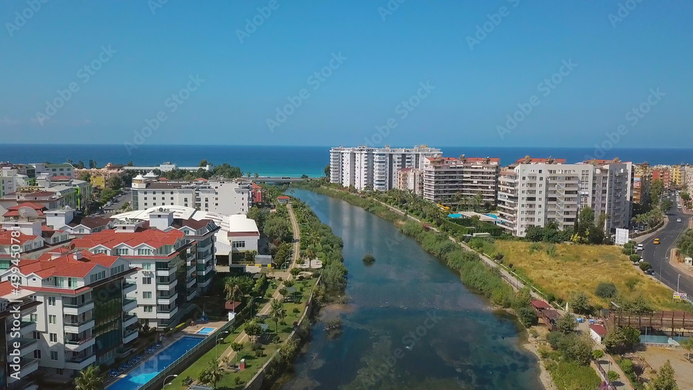 The view from the drone. Clip. View of the blue clear ocean near the resort area with a swimming pool and houses .