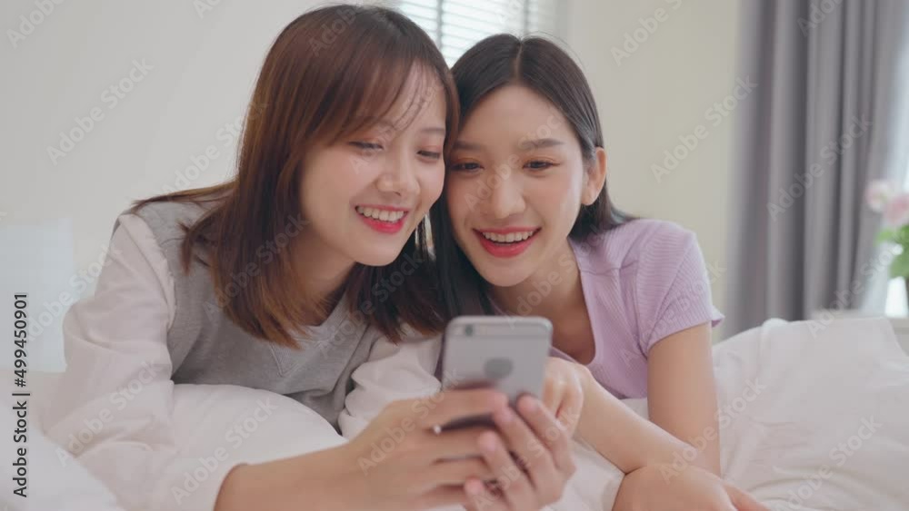 Young beauty Asian women LGBT lesbian happy couple laying on the bed using smartphone together in bedroom. LGBT lesbian couple together indoors concept. Spending nice time at home Young beauty Asian women LGBT lesbian happy couple laying on the bed using smartphone together in bedroom. LGBT lesbian couple together indoors concept. Spending nice time at home