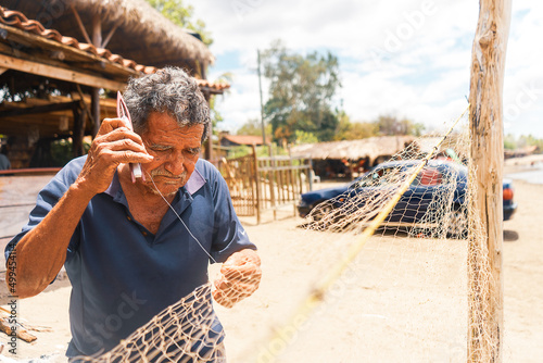 Elderly Latino fisherman weaving a cast net used to hunt squid in a poor rural area of a beach in Leon, Nicaragua. Lifestyle of the indigenous communities of Central America. photo