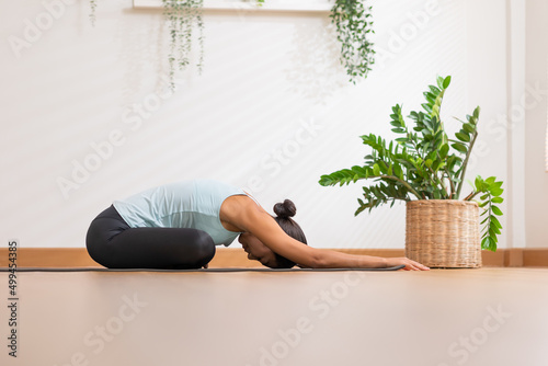 Side view of Asian woman wearing green sportwear doing Yoga exercise,Yoga Child’s pose or Balasana,Calm of healthy young woman breathing and meditation with yoga at home,Exercise for wellness life photo