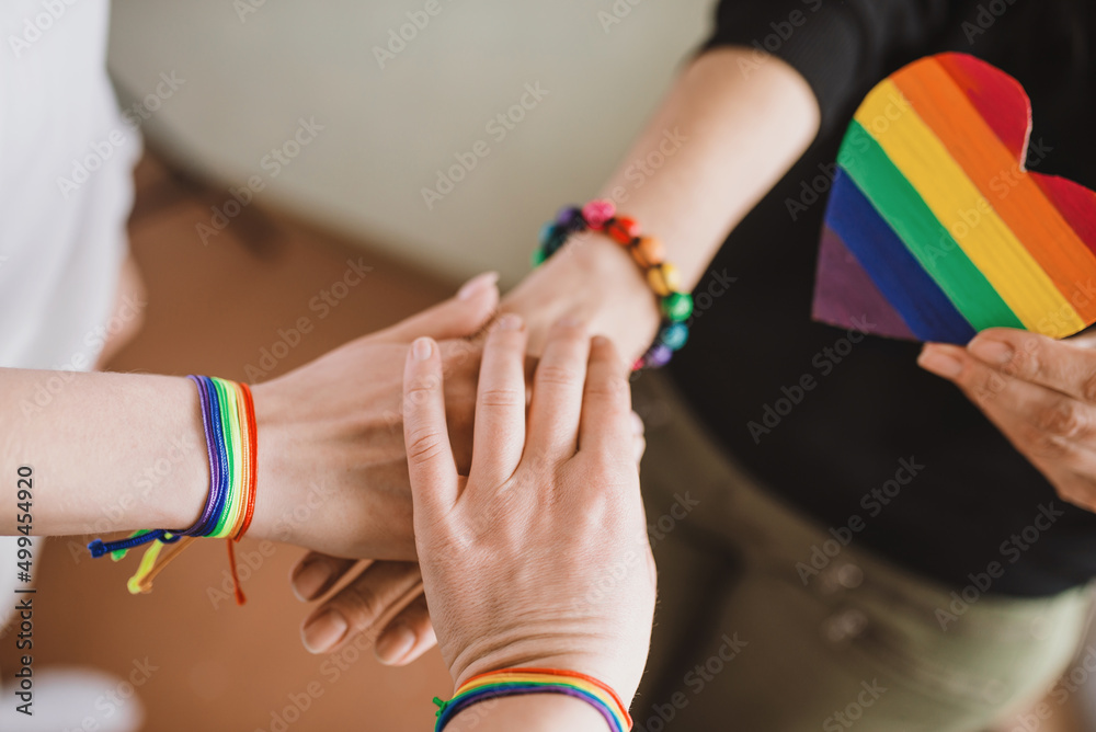 LGBT pride celebration. Hands of a group of three people with LGBT flag bracelets