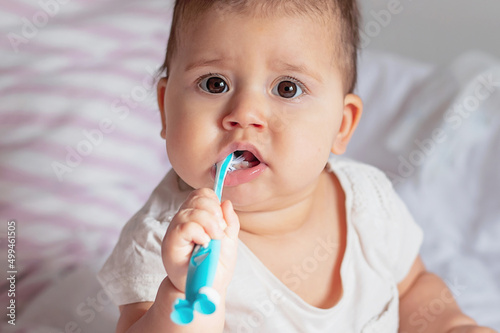 Baby girl Brushing Teeth on bed  light background  close-up  portrait