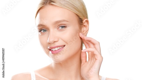 Close-up beauty portrait of young Caucasian woman touches her jaw and cheek and smiles for the camera on white background | Skin care commercial concept