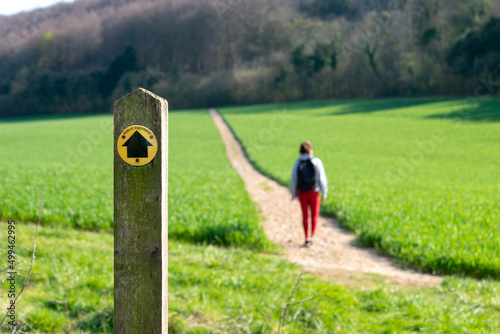 Photography Public footpath sign in the countryside with a hiker on the path.