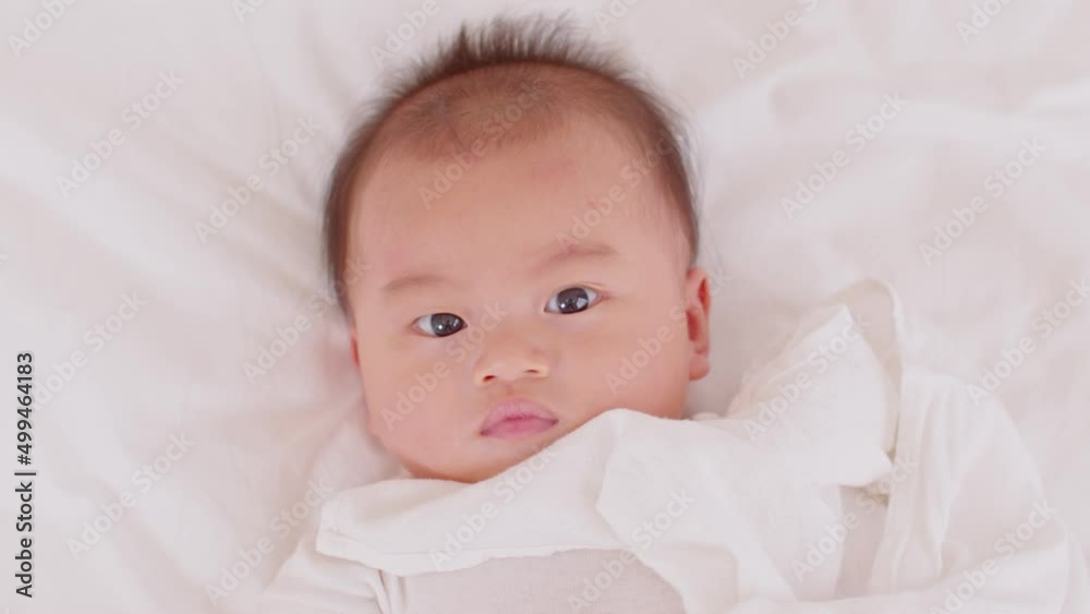 Top view happy newborn baby lying on a white bed and blanket comfortable and safety.Cute Asian newborn smile looking around on bed.Happy and Good moment.Newborn Baby Care concept Top view happy newborn baby lying on a white bed and blanket comfortable and safety.Cute Asian newborn smile looking around on bed.Happy and Good moment.Newborn Baby Care concept