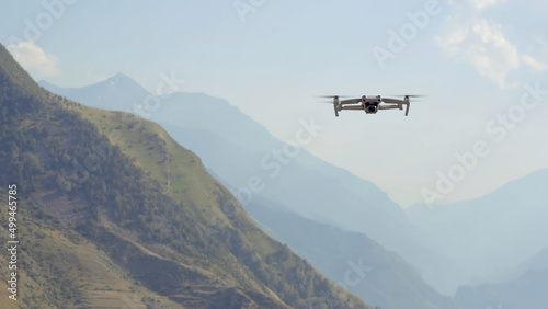 Aerial view of a quadcopter flying above green mountains on morning haze background. Action. Drone filming video of natural landscape.