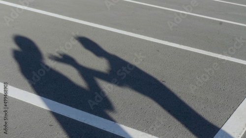 The silhouettes of two young men during angry conflict. HDR. Shadows of arguing friends with each other on the background of parking asphalt.