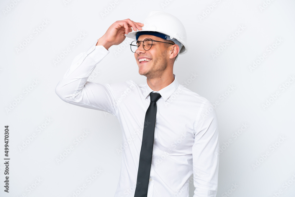 Young architect caucasian man with helmet and holding blueprints isolated on white background smiling a lot