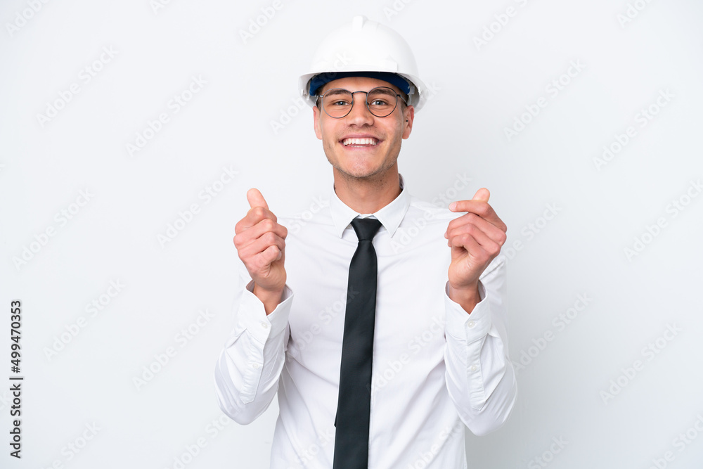 Young architect caucasian man with helmet and holding blueprints isolated on white background making money gesture