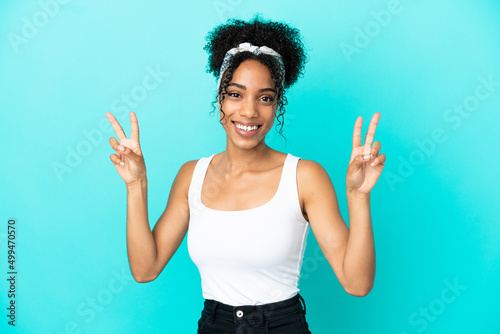 Young latin woman isolated on blue background showing victory sign with both hands