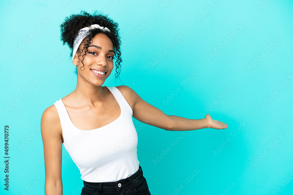 Young latin woman isolated on blue background extending hands to the side for inviting to come Young latin woman isolated on blue background extending hands to the side for inviting to come