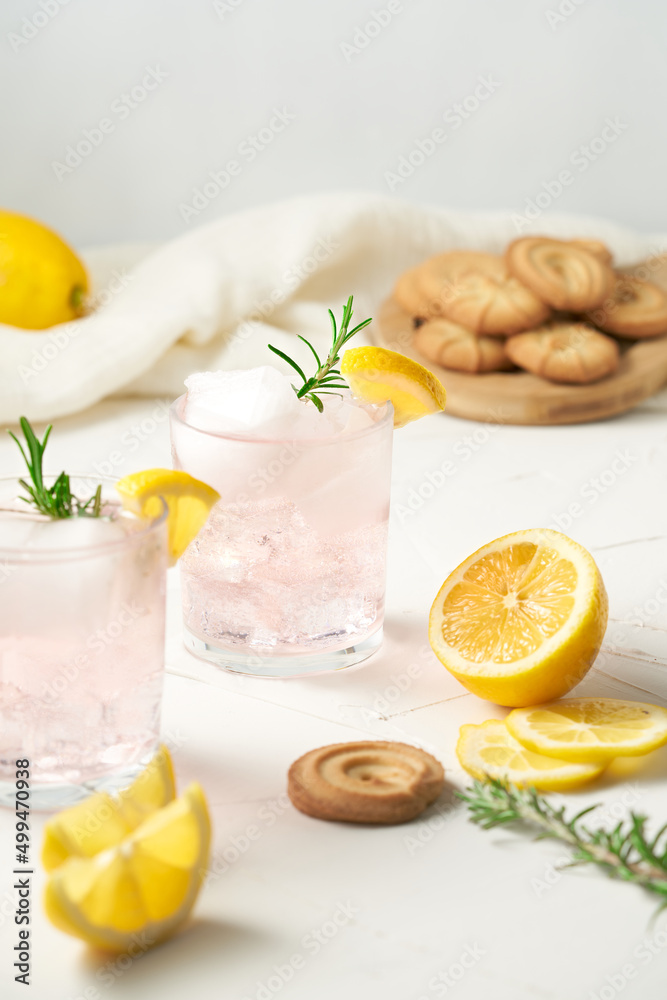 Summer refreshing drinks. Pink lemonade with juicy lemon slices, rosemary and butter tea cookies. Colorful kitchen scene, bright background. Summer refreshing drinks. Pink lemonade with juicy lemon slices, rosemary and butter tea cookies. Colorful kitchen scene, bright background.