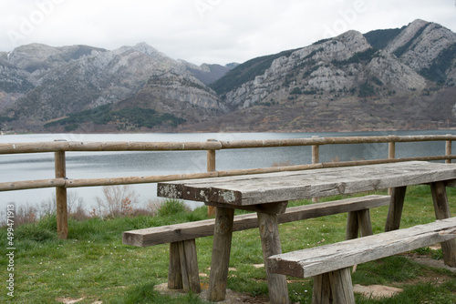 Picnic area with wooden table and bench. Magnificent view of the water reservoir at Caldas de Luna and the mountains around. Spain