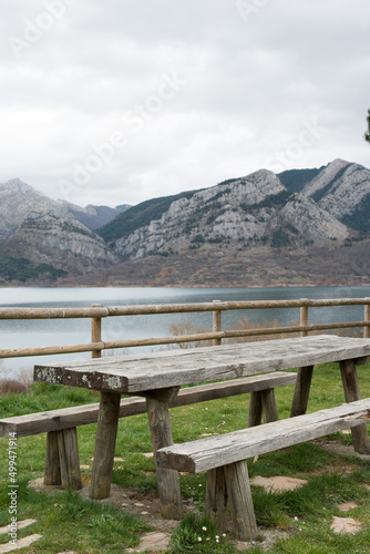 Picnic area with wooden table and bench. Magnificent view of the water reservoir at Caldas de Luna and the mountains around. Spain