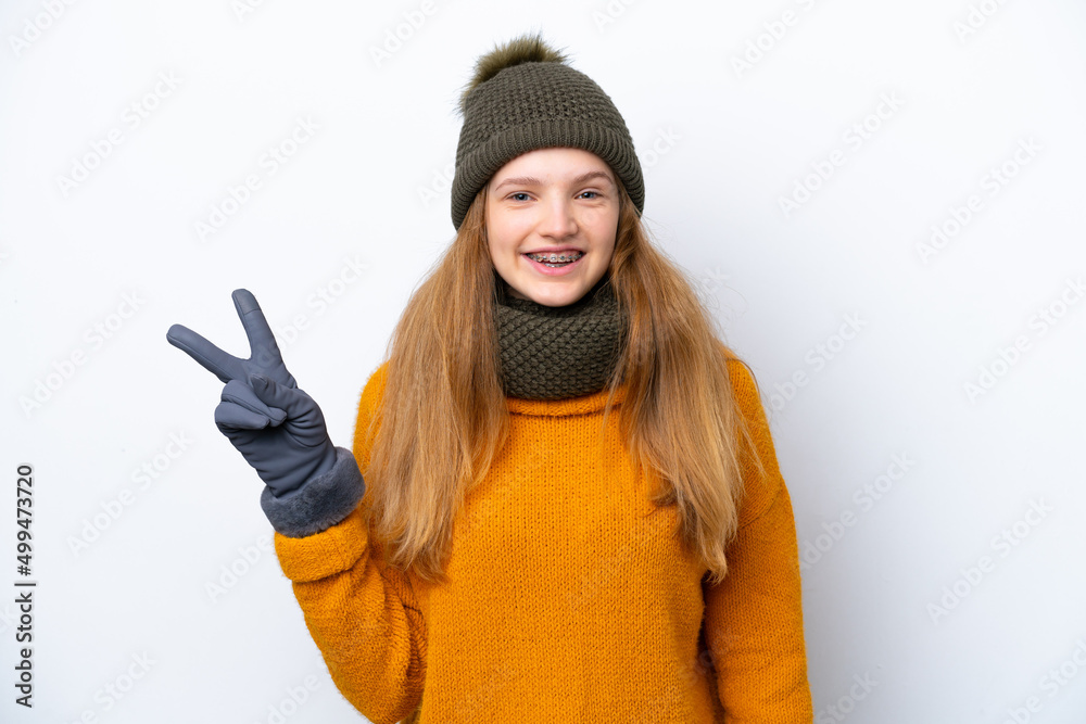 Teenager Russian girl wearing winter jacket isolated on white background smiling and showing victory sign Teenager Russian girl wearing winter jacket isolated on white background smiling and showing victory sign
