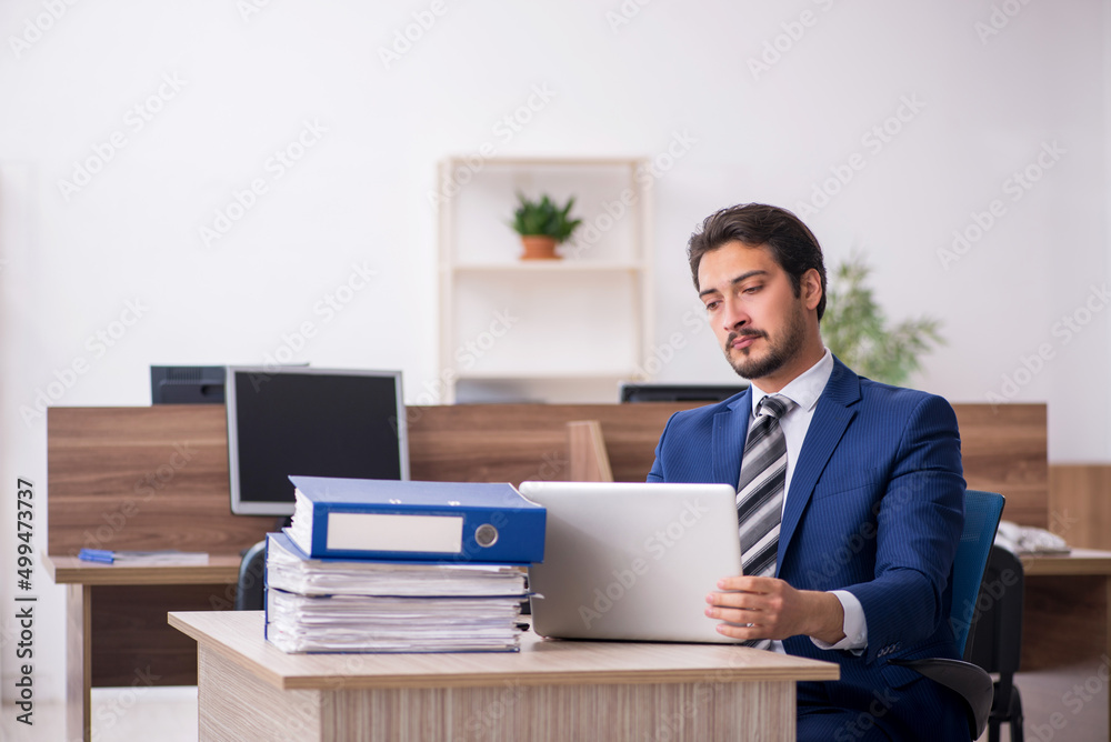 Young male employee and too much work in the office Young male employee and too much work in the office