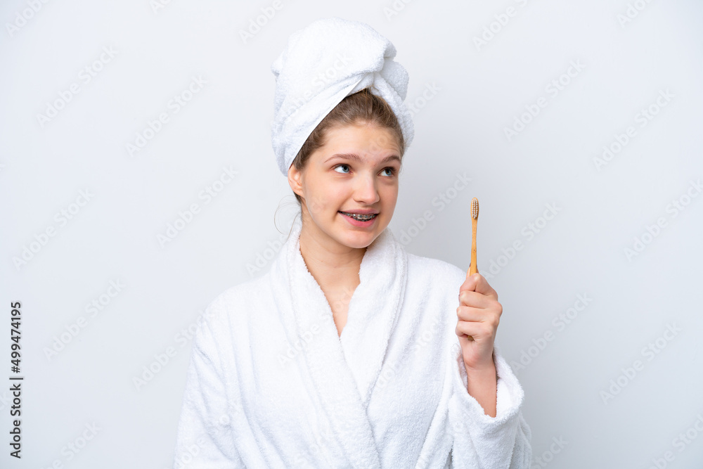 Teenager Russian girl brushing teeth isolated on white background looking up while smiling Teenager Russian girl brushing teeth isolated on white background looking up while smiling