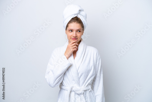 Teenager Russian girl in a bathrobe isolated on white background and looking up