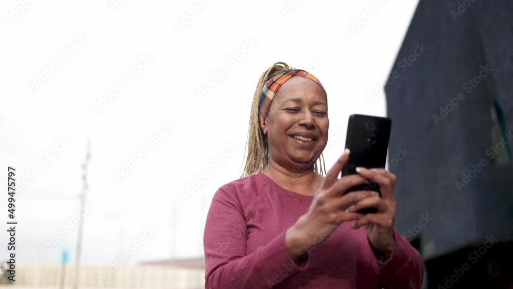 Senior African woman using mobile phone outdoor - Elderly and technology lifestyle concept Senior African woman using mobile phone outdoor - Elderly and technology lifestyle concept
