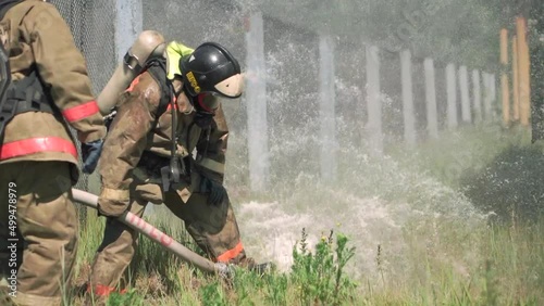 Firefighters. Clip. Two masked men who conduct exercises with a hose and water with special equipment and in a special uniform. photo