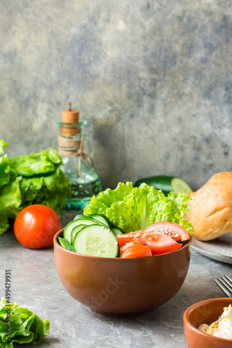 Fresh vegetable bowl with cucumber, tomato and lettuce on the table at home. Vertical view