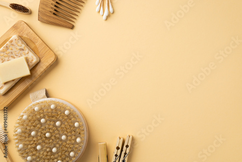 Top view photo of spa accessories anti-cellulite washcloth toothbrushes soap on bamboo stand hairbrush cotton buds and clothespins on isolated beige background with blank space