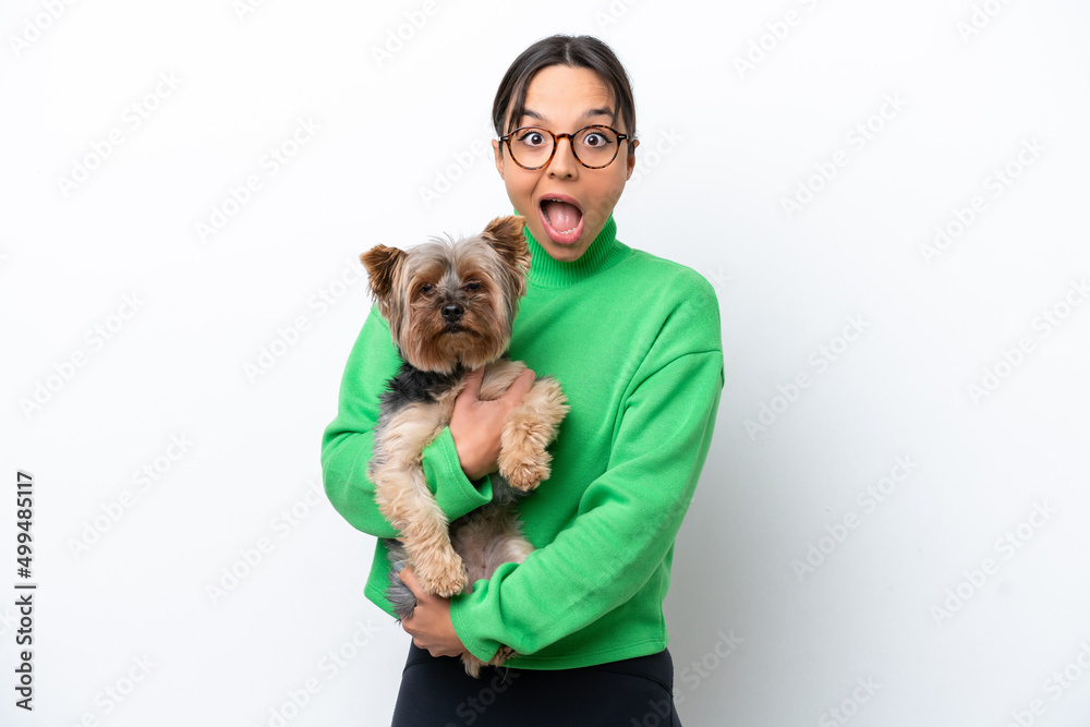 Young hispanic woman holding a dog isolated on white background with surprise and shocked facial expression Young hispanic woman holding a dog isolated on white background with surprise and shocked facial expression