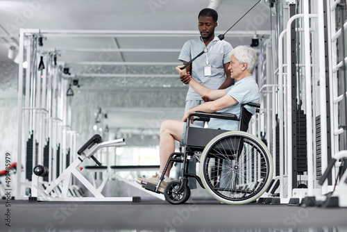 Side view portrait of senior man in wheelchair doing exercises in gym at healthcare clinic, copy space © Seventyfour