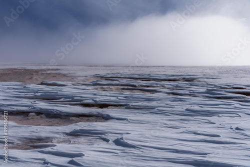 Sastrugi or glacial accident created by the erosion of the snowy surface by the action of the wind, snowy landscape with mist lurking, Sierra Nevada, Granada. photo