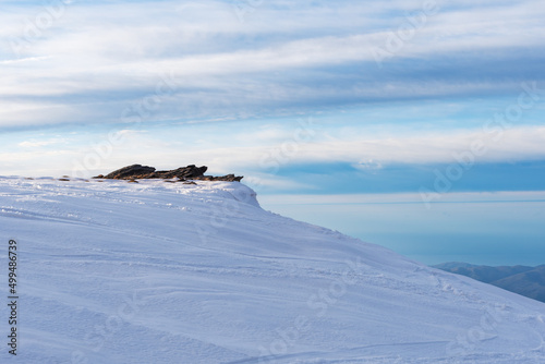View from a summit of Sierra Nevada of some rocks in winter  with everything snowed  in the background some mountains near the Mediterranean Sea.