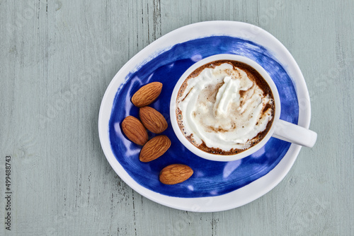Canvas Print Cup of coffee with whipped cream, almonds on a blue wooden table