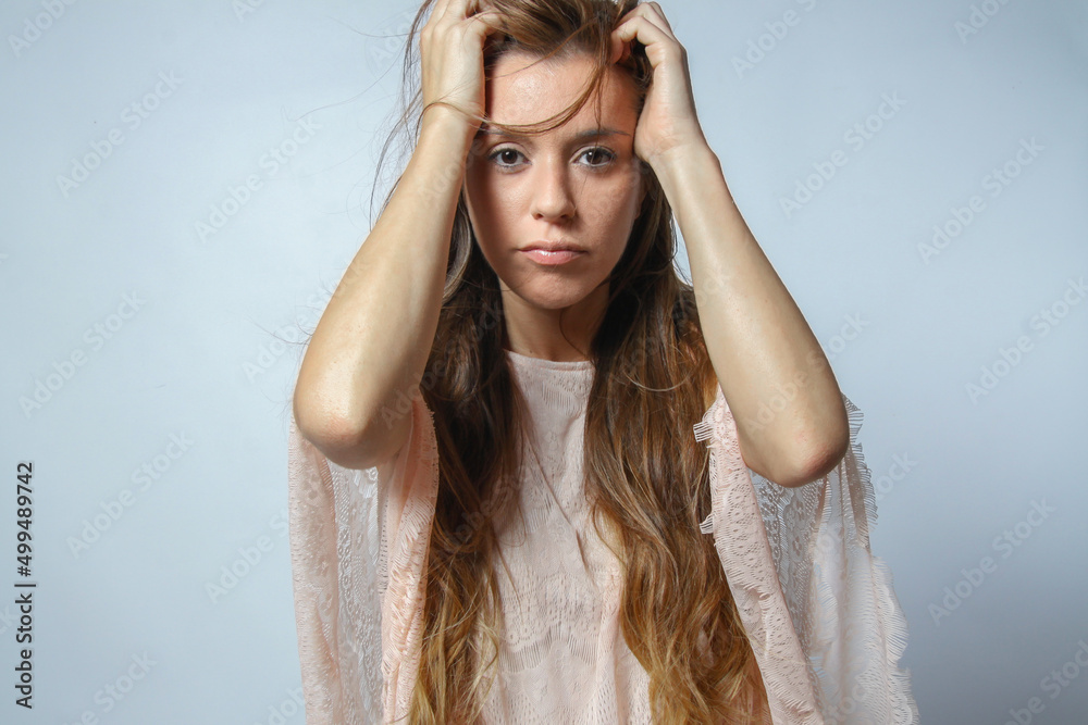 Young hispanic woman with migraine expression looking at camera with hands on head isolated on grey background. Human emotions concept. Young hispanic woman with migraine expression looking at camera with hands on head isolated on grey background. Human emotions concept.