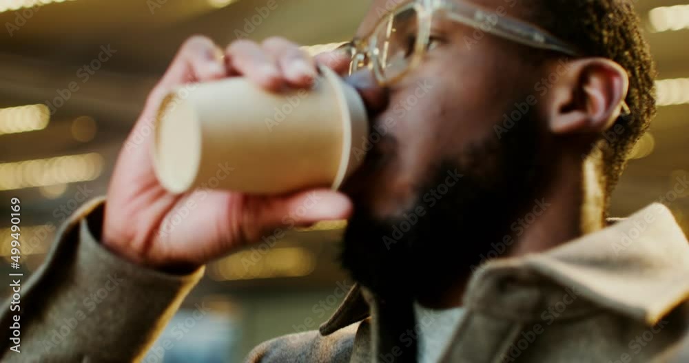 African-American man drinks coffee while walking around business center of city