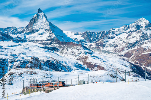 Red train climbing up to Gornergrat station with view of Matterhorn against clear blue sky. Beautiful Zermatt. 