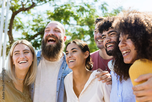 Young group of diverse friends having fun in a sunny day - Multiracial best friends enjoying time together outdoors - United millennial people laughing