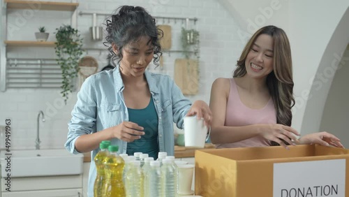 Volunteer concept of 4k Resolution. Asian women packing food in a donation box together at home. Consumer goods donated to help the victims.