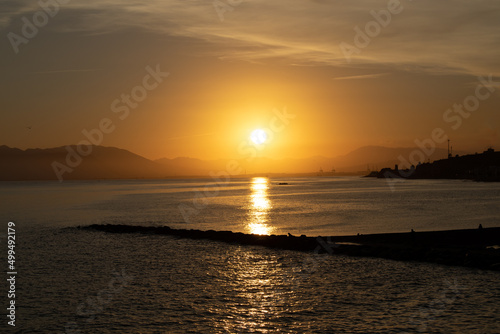 puesta de sol de un cielo anaranjado con un embarcadero que sale de la playa  © jose