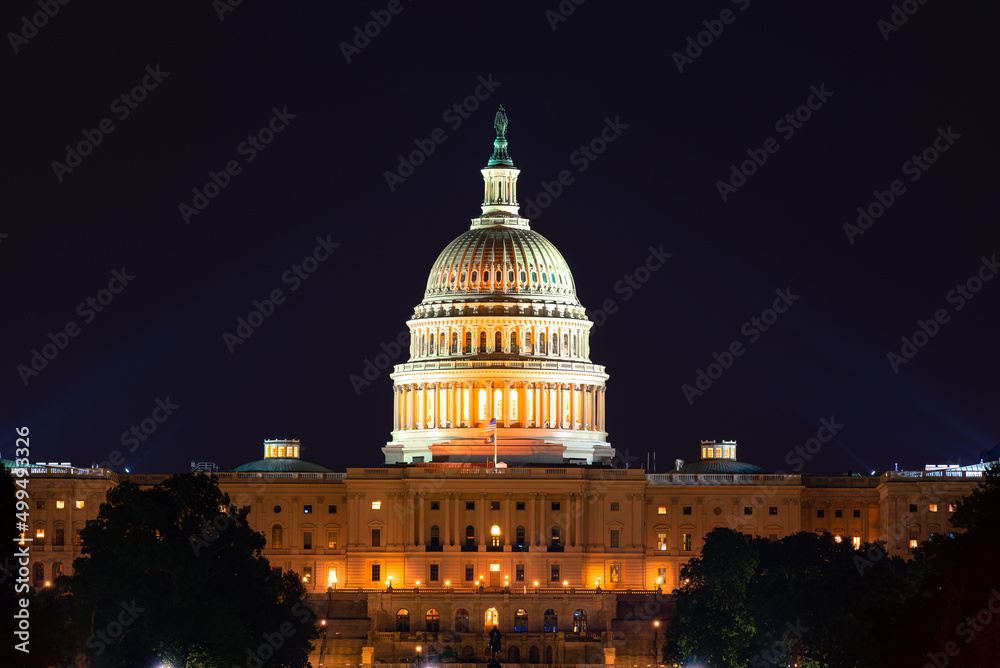 United States Capital Building at night with spot lights illuminating the dome.