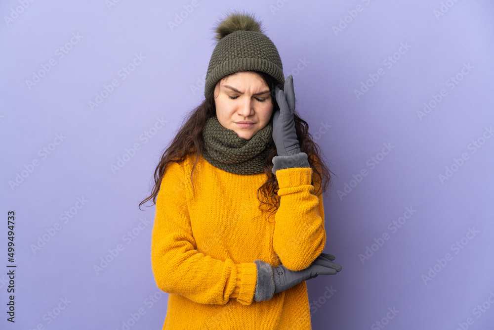 Teenager Russian girl with winter hat isolated on purple background with headache Teenager Russian girl with winter hat isolated on purple background with headache