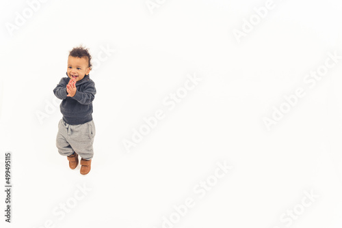 handsome toddler standing on the floor applauding and smiling. High quality photo