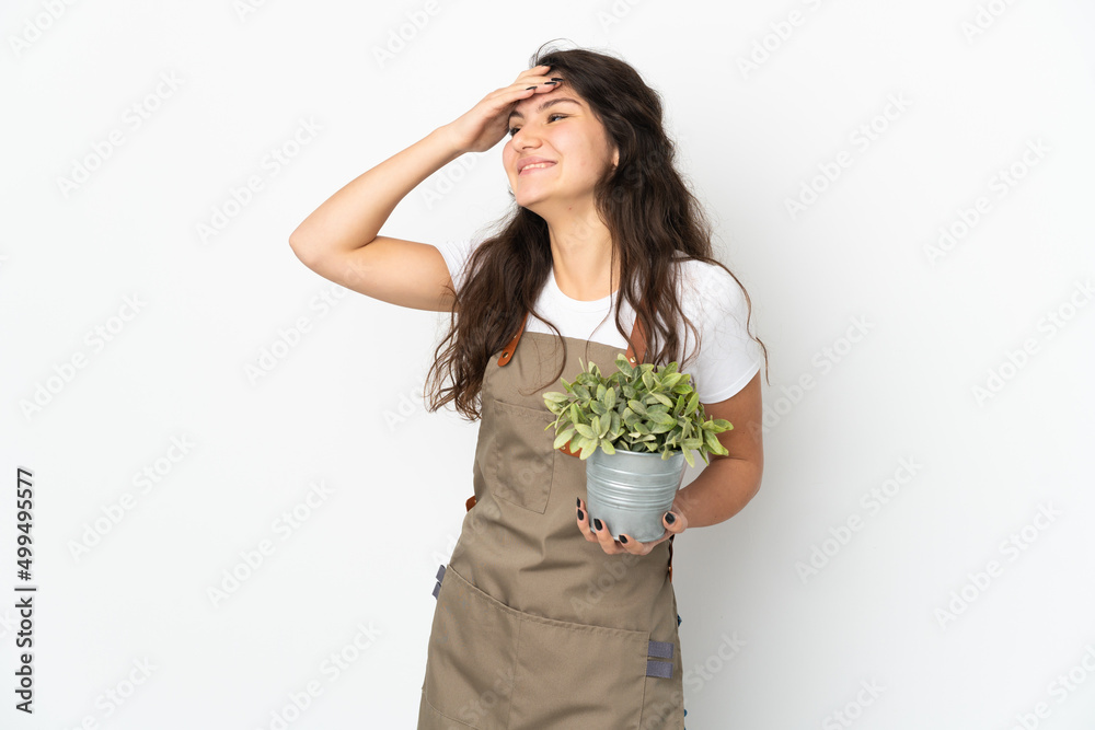 Young Russian gardener girl holding a plant isolated smiling a lot Young Russian gardener girl holding a plant isolated smiling a lot