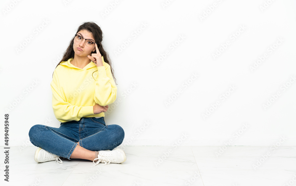 Teenager Russian girl sitting on the floor thinking an idea Teenager Russian girl sitting on the floor thinking an idea