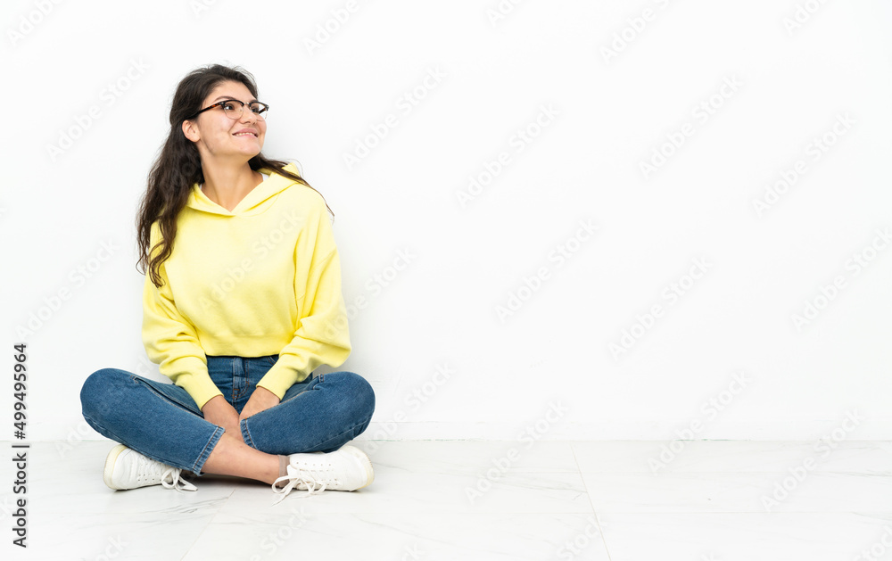 Teenager Russian girl sitting on the floor looking to the side and smiling Teenager Russian girl sitting on the floor looking to the side and smiling