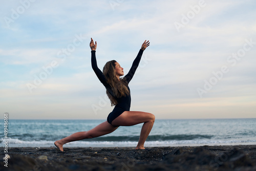 woman doing a yoga practice at the beach while a beautiful sunset