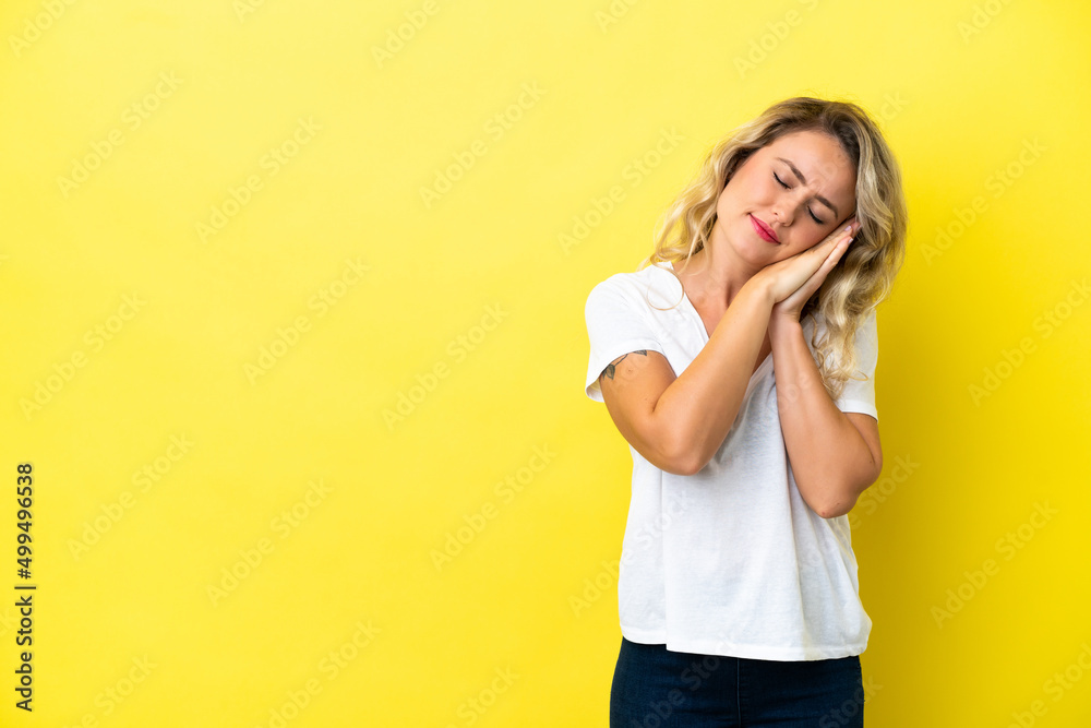Young Brazilian woman isolated on yellow background making sleep gesture in dorable expression Young Brazilian woman isolated on yellow background making sleep gesture in dorable expression