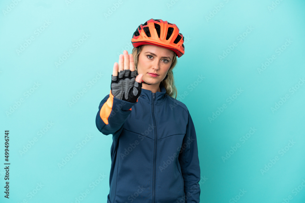 Young cyclist woman isolated on blue background making stop gesture Young cyclist woman isolated on blue background making stop gesture